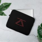 A sleek black laptop sleeve featuring the zSecurity logo in red, shown on a table with leaves as decor, designed to protect laptops in style.